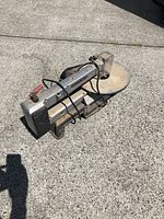 Dremel 16 inch scroll saw showing side profile, power switch, power cord and blade arm.