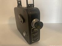 Front and side view showing the lens and identifying labels including model and manufacturer details.