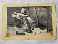 Front view of vintage black and white hockey photo card showing Al Rollins in goalie gear near the net. Card has visible wear and stains.