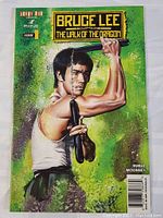 Cover front of Bruce Lee comic book showing Bruce Lee holding nunchucks with green splash background.