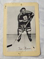 Black and white photo card of Fern Flaman on ice, mounted on aged cream card showing wear, marks, and discoloration.