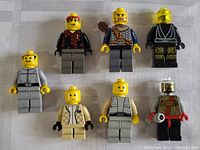 Top-down photo showing all seven LEGO minifigures laid out on a white background