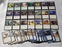 Layout of Magic The Gathering cards showing a variety of colors including green, black, white and blue with creatures and spells visible.