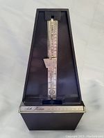 Full front view of black Seth Thomas wind-up metronome showing brand logo, pendulum, and tempo scale.