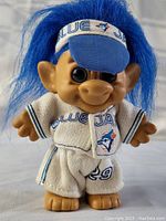Front view of the troll doll showing its blue hair, Blue Jays visor, and uniform with number 29.