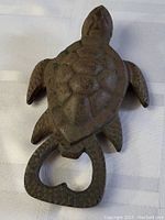 Top down view of the turtle-shaped cast metal bottle cap opener showing textured shell and heart-shaped opener at tail end.