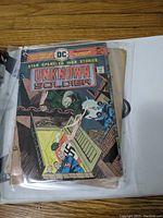 Image of vintage DC Comics The Unknown Soldier No 198 comic book in a protective sleeve. Cover shows wartime illustration with soldiers, a ghostly figure, and a swastika, indicating WWII theme. The comic is visibly worn and aged.