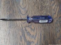 Fuller electrician's screwdriver with blue acetate handle showing product code on hardwood floor