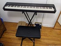 Roland FP-E50 digital piano on X-style folding stand with padded bench