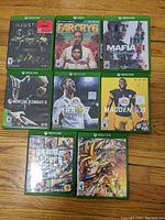 Full lot showing 8 Xbox One game cases arranged on a floor surface with visible cover art.