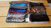 Top view of 38 mixed vintage men's neckties featuring various colors and patterns laid out on a table in two stacks.