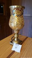 Full view of the lamp on a table showing the golden mosaic glass shade and brass base.