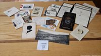 Overview of all cards and notices laid flat including silhouette portrait, postcards, certificates, and death notices.