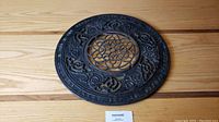 Front view of round cast iron stove grate showing detailed floral and scrollwork design with manufacturer text around edge.