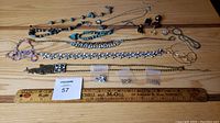 Wide top-down photo of all jewelry laid out on wood background including necklaces, bracelets, earrings, and pendant.