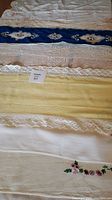 Photo showing all eight vintage dresser scarves stacked, highlighting varying lengths, colors, and lace details.