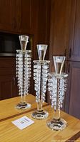 Photo of set of three facetted glass candlesticks of varying heights with hanging crystal drops.