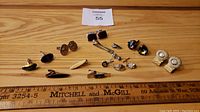 Photo of all items including cufflinks, tie tacks, and tie clips arranged on a wooden surface with a ruler for scale.