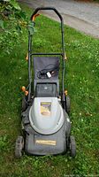 Front view of Remington battery lawnmower with collection bag, charger cable, and foldable handle on grass.