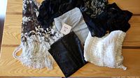 Overview of the lot showing multiple scarves and shawls in various fabrics and decorations on a wooden surface.