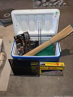 Photo showing assembled camping items including cooler, BBQ utensils, bamboo mat, and bingo game