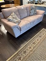 Front-right angle view of taupe suede-like couch with two floral pillows