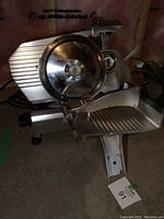 Front view of stainless steel meat slicer showing round blade and food carriage