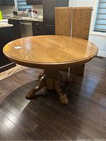 Round dining table with two leaves stored upright behind