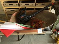 Metal wheelbarrow with Toro Super Blower, orange extension cord and umbrellas inside