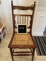 Front view of the antique chair showing Sheraton square back with floral detail and cane seat.