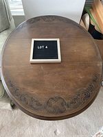 Top view of round drop leaf antique wooden table showing intricate inlaid and etched design around edges.