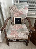 Full view of upholstered armed side chair with floral fabric and wooden arms and legs, showing overall condition and pattern of fabric.