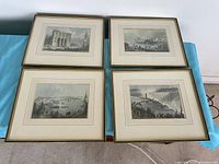 Four framed prints laid out on a blue surface showing four different Canadian scenes.
