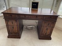 Front view of the mahogany stained desk showing the top row of three drawers and two banks of larger drawers beneath.