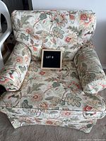 Front view of the occasional chair showing the floral and leaf patterned fabric upholstery.