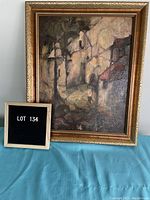 Framed oil painting depicting a Mexican landscape with trees and buildings in earth tones, signed in lower right corner.