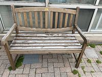Front view of the wooden bench showing vertical slat backrest and seat with weathered wood finish.