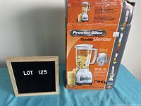 Photo showing the Proctor Silex blender original box featuring image of blender with bananas and juice. Orange color with product information and branding.