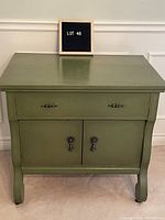 Front view of vintage moss green cabinet with drawer and cupboard closed.