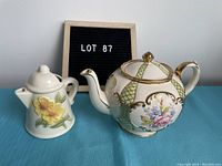 Photo of the Sadler teapot and sunflower creamer side by side on blue cloth background with LOT 87 sign