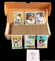Card set displayed in box showing many individual football cards arranged in stacks, plus star player cards in front.