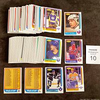 Wide view of hockey cards sorted in stacks with focus on visible player cards and checklist cards.