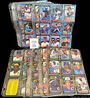 Two thick binders filled with baseball cards displayed in plastic sleeves, cards visible with player images and numbering.