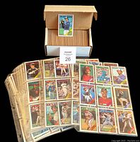 Two sets of 1988 O.P.C. baseball cards. One set arranged in binder pages showing multiple cards per page. The other set stacked inside a white box with a single card displayed standing on top of the box.