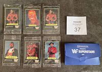 Six sealed WWF 1991 Superstars cards and blue custom plastic envelope arranged on surface