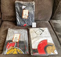 Three sealed Ottawa Senators t-shirts in original packaging, one black, one grey Starter brand and one white Puma brand shirt.