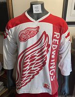 Front view of the white and red Detroit Red Wings hockey jersey with large wing logo, vertical team name, and Starter patch near hem.