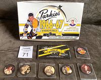 Photo showing the white wax box with yellow and black Parkies 1966-67 Parkhurst branding and Bobby Orr image, empty pack wrapper, and six insert coins each in clear protective holders arranged on gray surface.
