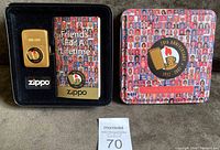 Lighter in black foam tray next to booklet and closed metal presentation box showing collage design and commemorative logo