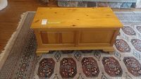 Front and top side view of pine wood blanket box on a patterned carpet.